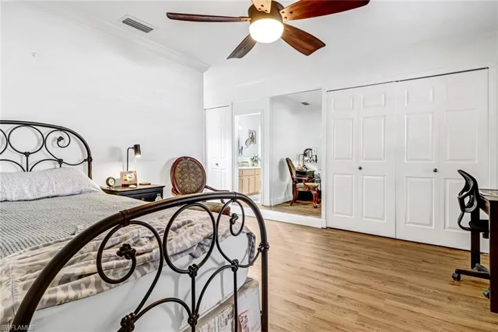 Bedroom featuring light wood-type flooring, ceiling fan, crown molding, and connected bathroom