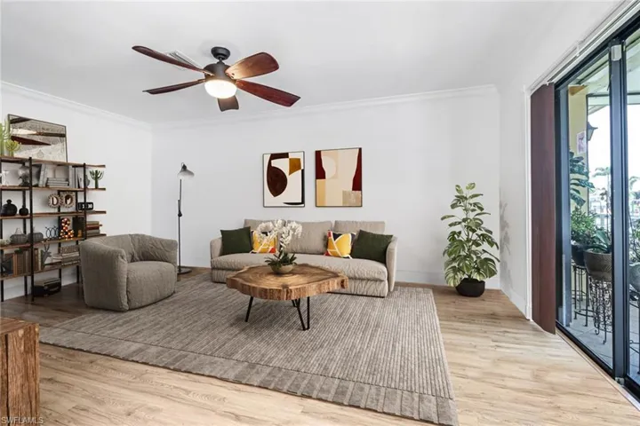 Living room with light wood-type flooring, crown molding, ceiling fan, and a wealth of natural light