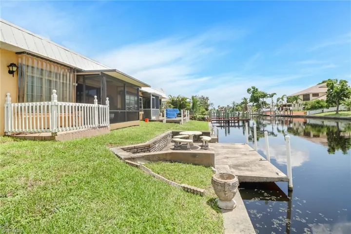 View of dock with a lawn and a water view