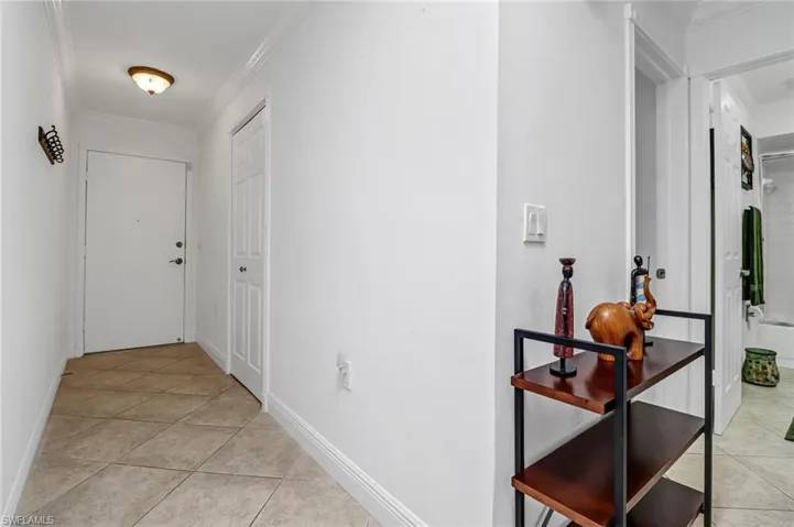 Corridor with light tile patterned flooring and ornamental molding