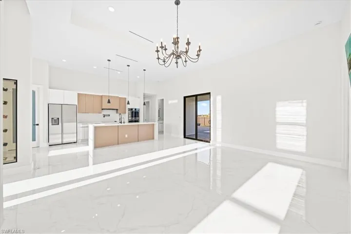 Kitchen with open floor plan, stainless steel built in fridge, a kitchen island with sink, modern cabinets, and suspended lighting