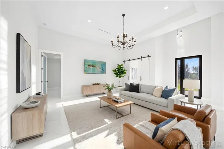 Living room featuring a barn door, suspended lighting, and a high ceiling