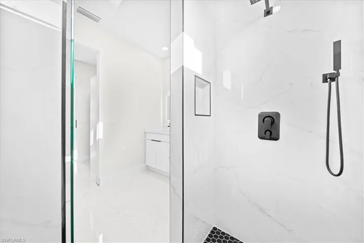 Bathroom featuring vanity, a marble finish shower, recessed lighting, and light marble finish floors