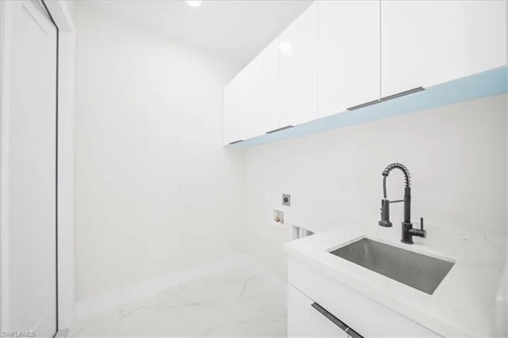 Laundry room featuring light marble finish floors, cabinet space, hookup for an electric dryer, and washer hookup