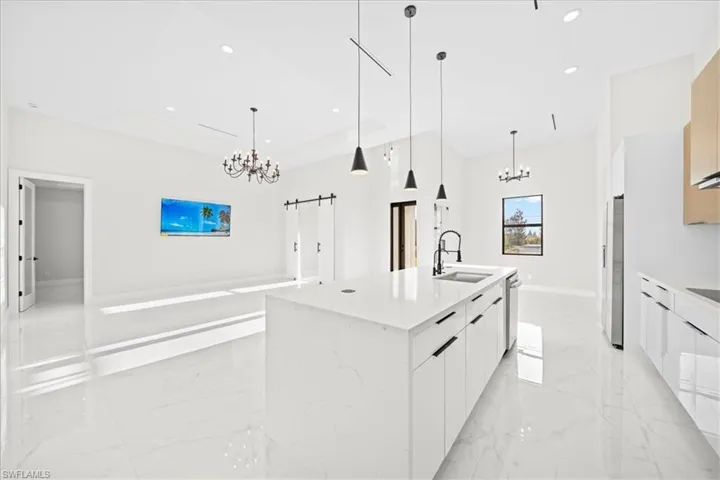 Kitchen featuring a chandelier, modern cabinets, a kitchen island with sink, light stone counters, and open floor plan