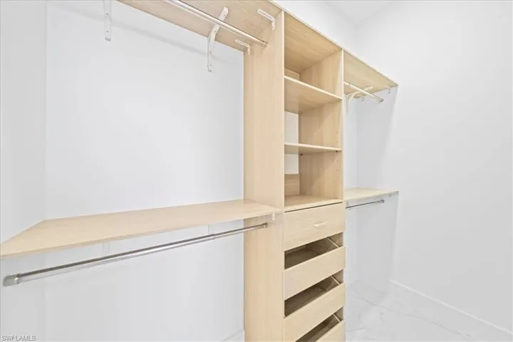 Walk in closet featuring light marble finish flooring