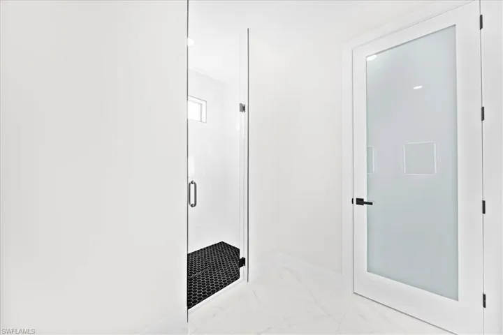Full bath with a marble finish shower and light marble finish floors