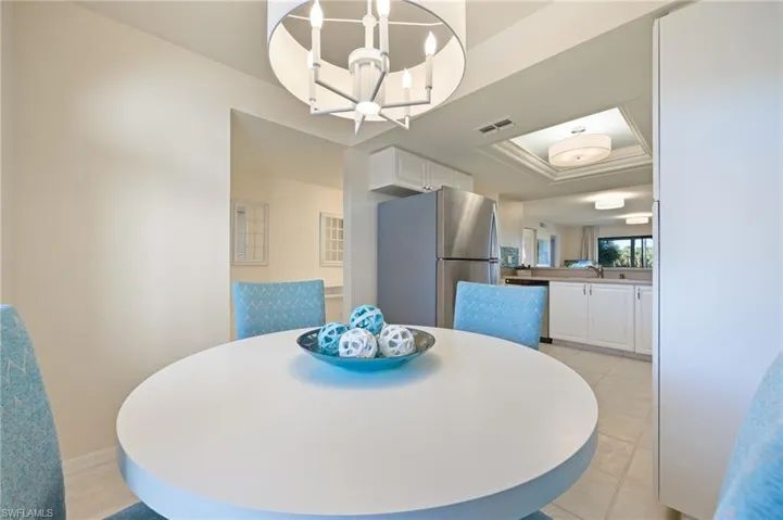 Dining area with a raised ceiling, light tile patterned flooring, and a chandelier
