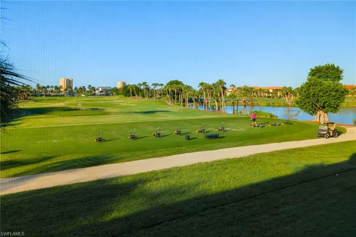 View from unit #1577 of property's community driving range and lake with clubhouse off in the distance.