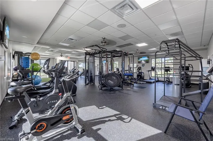 Exercise room with a paneled ceiling, plenty of natural light, and a ceiling fan