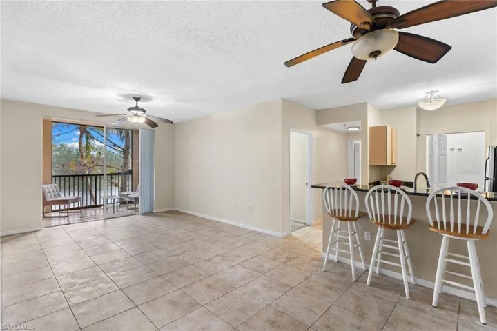 Kitchen featuring ceiling fan, dark countertops, a kitchen breakfast bar, a textured ceiling, and a peninsula