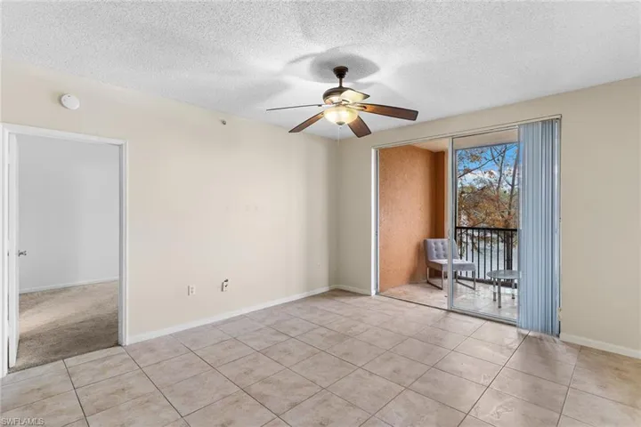 Empty room featuring a textured ceiling, a ceiling fan, and light tile patterned flooring