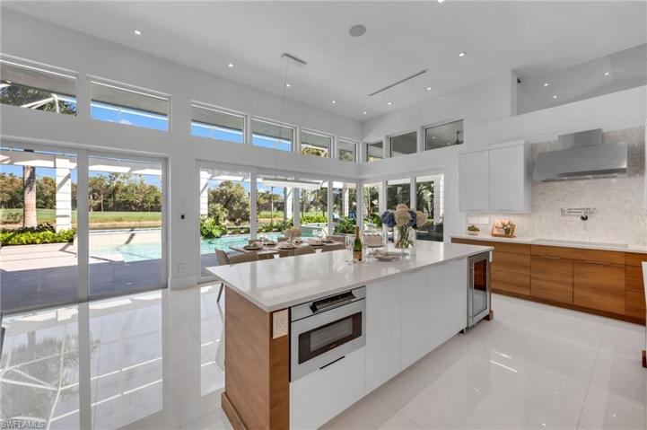 This sleek yet inviting kitchen has finishes of quartz, wood cabinetry, double ovens, extra beverage refrigerator and induction cooktop.
