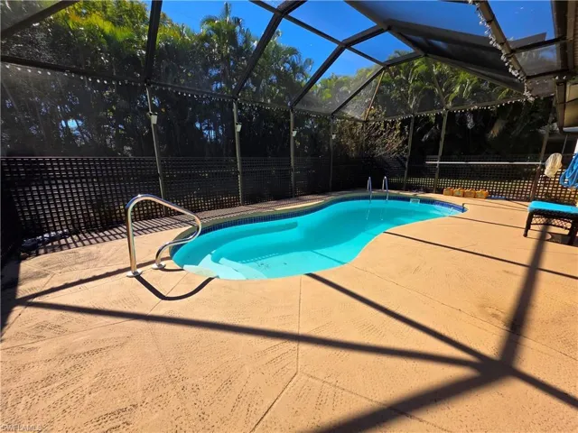 View of pool with glass enclosure, a patio area, a fenced backyard, and a sunroom