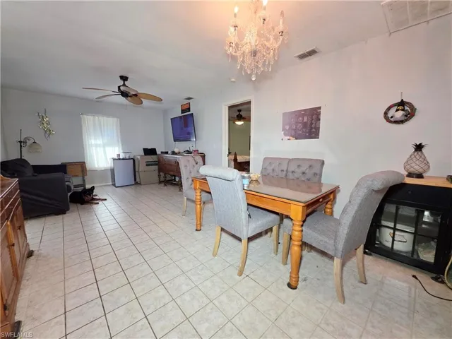Dining space with a ceiling fan, a chandelier, and an office area