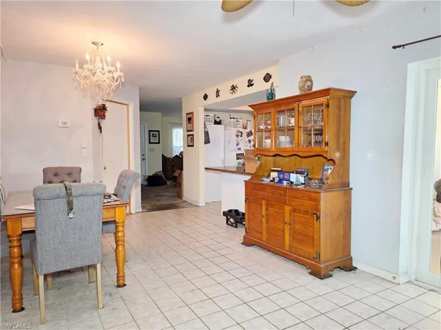 Dining space with ceiling fan, a chandelier, and light tile patterned flooring