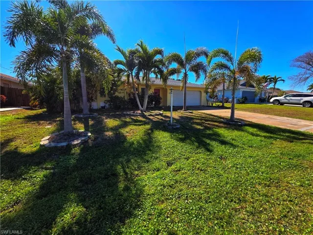View of front of house with concrete driveway, a garage, a front lawn, and stucco siding