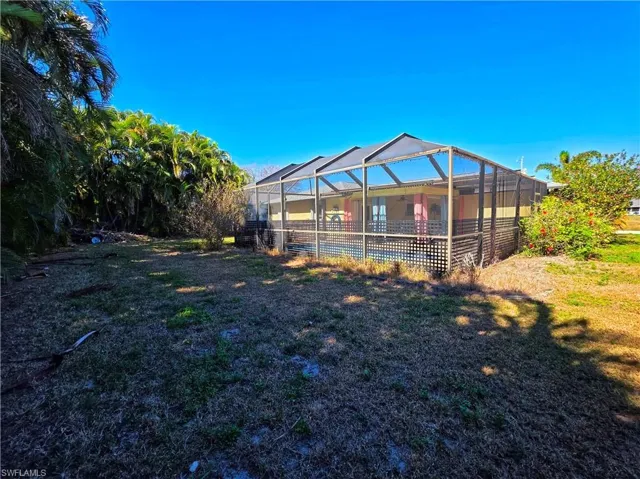 Back of house featuring glass enclosure, a lawn, and a sunroom