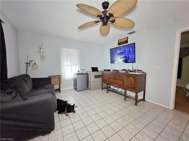 Living room with ceiling fan, light tile patterned floors, and a desk