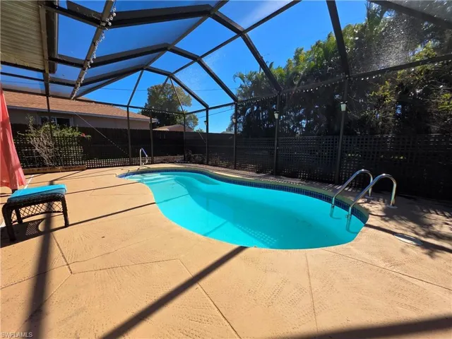 View of pool with glass enclosure, a fenced backyard, a sunroom, and a patio area