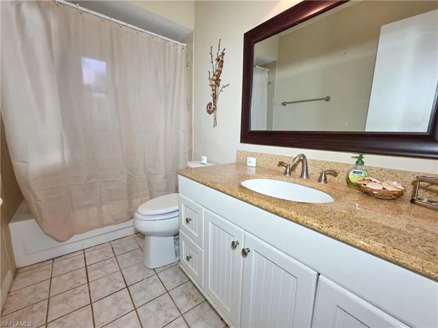 Full bath with vanity, shower / bath combo, and light tile patterned flooring