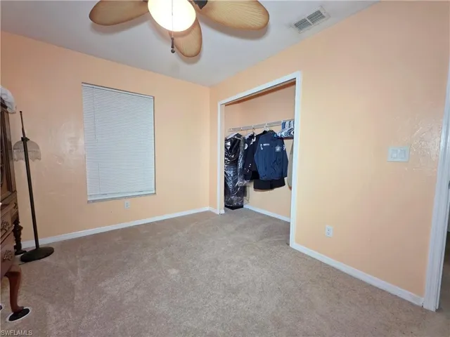 Unfurnished bedroom featuring carpet flooring, ceiling fan, and a closet