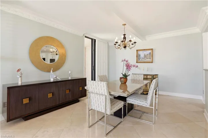 Dining area featuring crown molding, hanging lights, light tile patterned flooring, and beamed ceiling