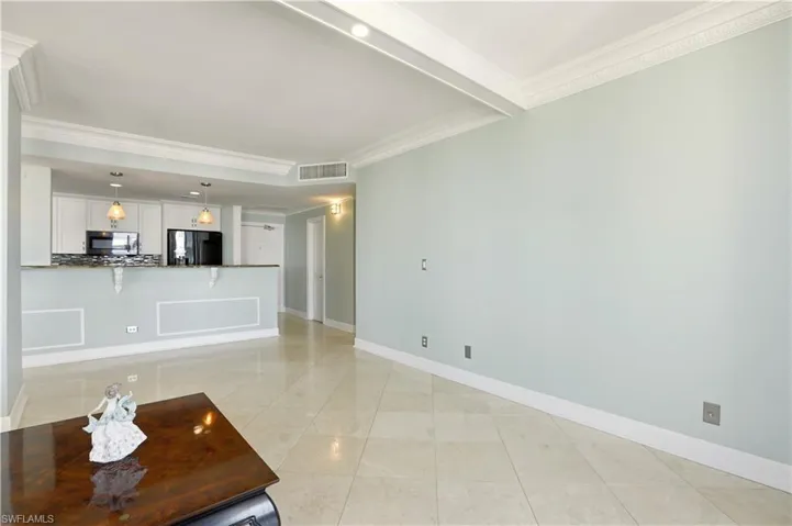 Unfurnished living room with crown molding and light tile patterned floors
