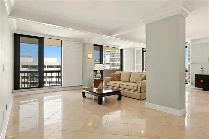 Living room featuring beamed ceiling, crown molding, expansive windows, and light tile patterned floors