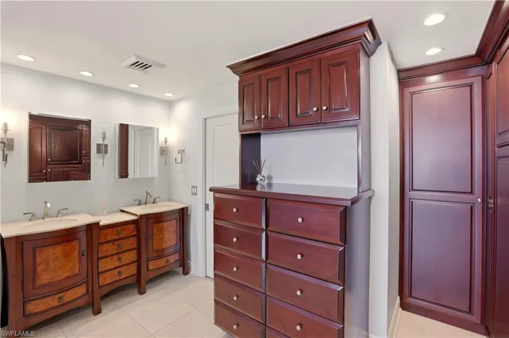 Full bathroom with two vanities, recessed lighting, and light tile patterned flooring