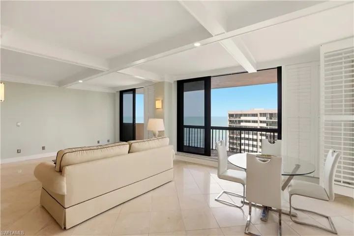 Great room featuring floor to ceiling windows, coffered ceiling, healthy amount of natural light, a water view, and light tile patterned floors