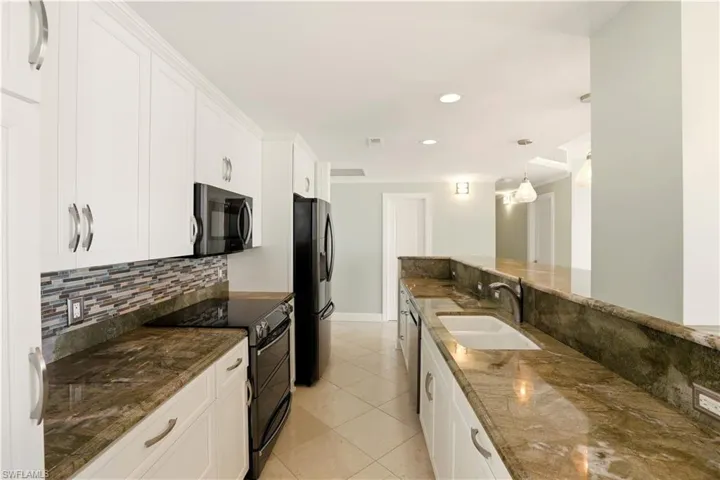 Kitchen with range with two ovens, white cabinetry, fridge with ice dispenser, and light tile patterned floors