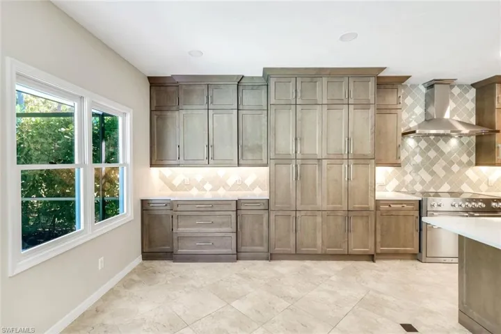 Kitchen showcasing abundant custom cabinetry and generous storage with designer backsplash detail.