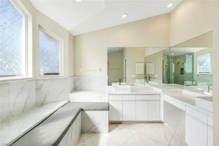 Primary bathroom highlighted by a glass walk-in shower and relaxing built-in bench seating.