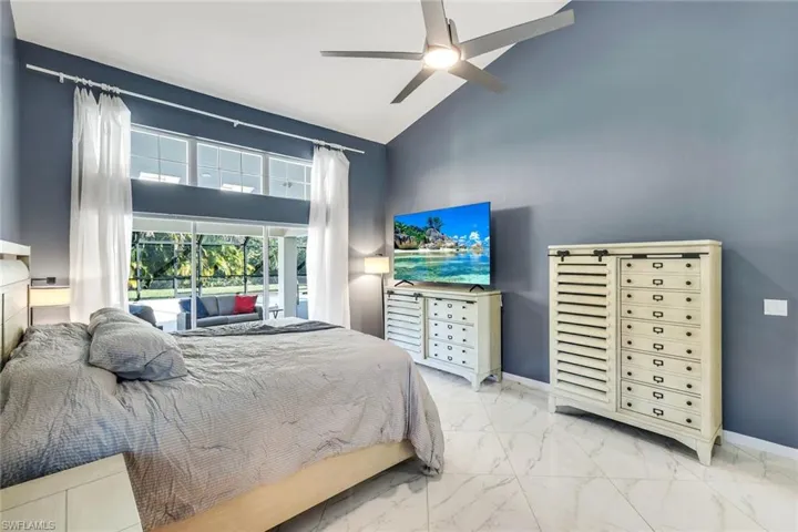 Spacious primary bedroom featuring vaulted ceilings, abundant natural light, and sliding glass door access to the outdoor living area.