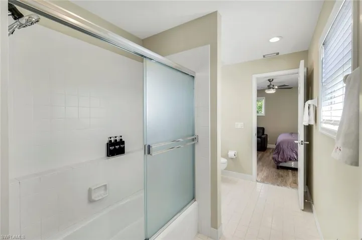 Jack-and-Jill bathroom featuring tub/shower combination with sliding glass doors and tile flooring.