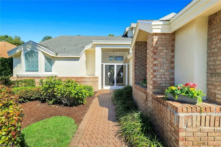 Welcoming front entry highlighted by brick accents, manicured landscaping, and charming walkway approach.