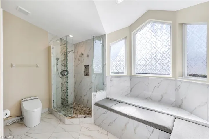 Primary bathroom highlighted by a glass walk-in shower and relaxing built-in bench seating.