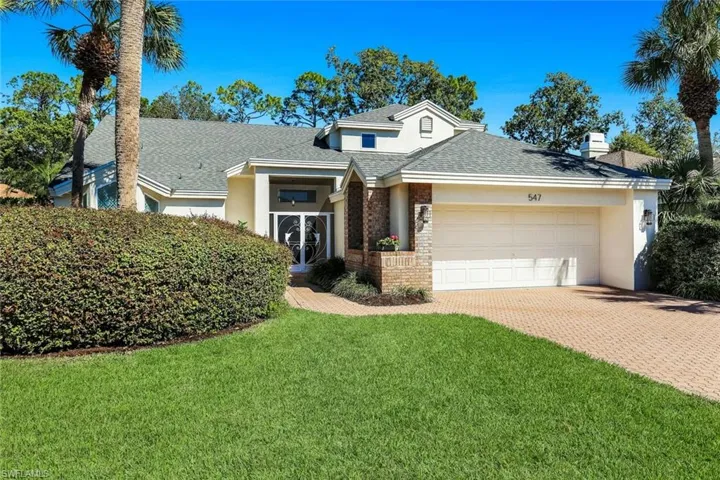 Beautifully maintained front exterior featuring mature landscaping, brick accents, and a welcoming covered entry.