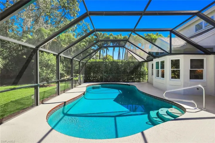 Screened pool oasis with spacious patio and lush tropical privacy.