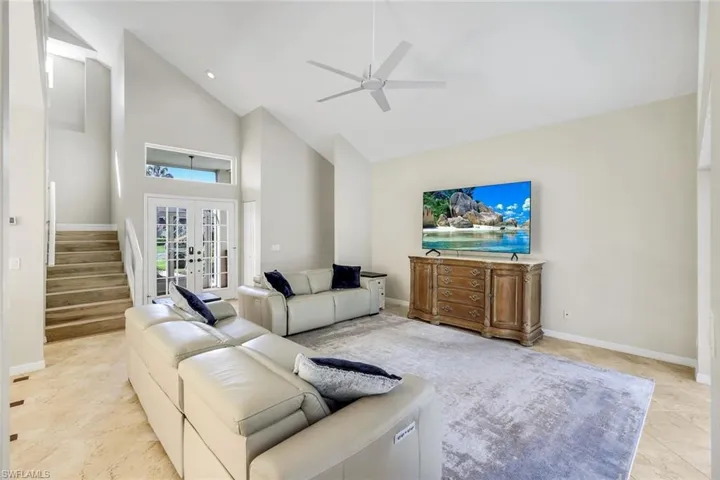Bright living space with vaulted ceilings, elegant French doors, and abundant natural light creating an open, airy feel.