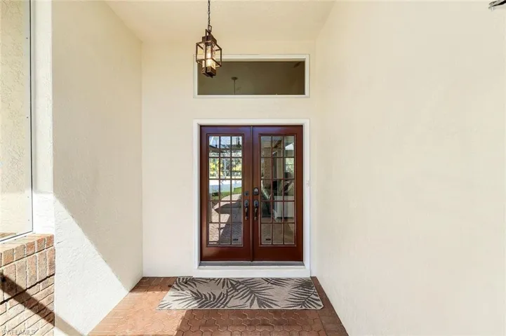 Elegant double-door entrance with transom window and covered entryway offering protection from the elements and discreet delivery space.
