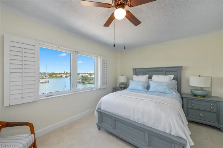 Carpeted bedroom with a textured ceiling, a water view, crown molding, and ceiling fan