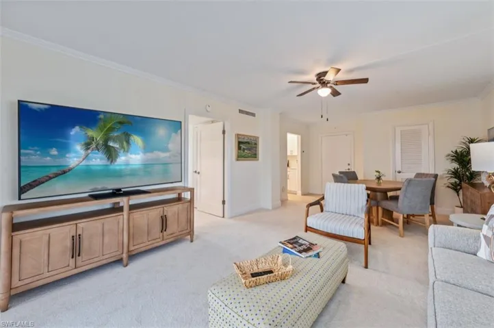Living area featuring crown molding, light carpet, and ceiling fan