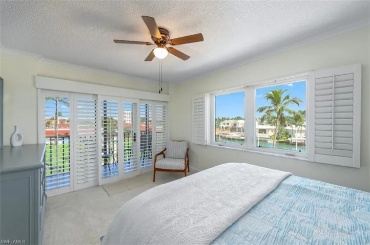 Bedroom featuring multiple windows, access to exterior, a textured ceiling, carpet, and ceiling fan