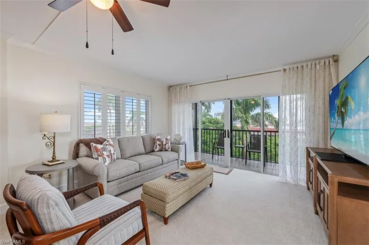 Living room featuring ornamental molding, light colored carpet, and ceiling fan