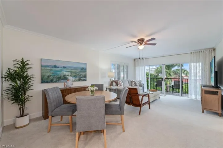 Dining space with light colored carpet, ceiling fan, and ornamental molding