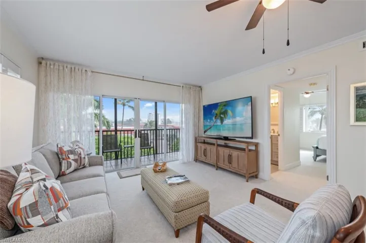 Carpeted living area featuring ornamental molding and ceiling fan