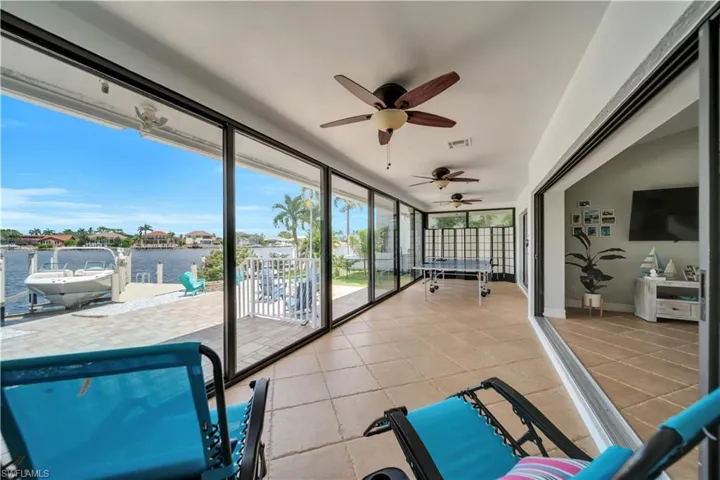 Sunroom / solarium with a water view, ceiling fan, and a patio area