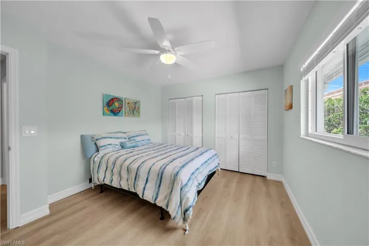 Bedroom with two closets, light wood-style flooring, and a ceiling fan
